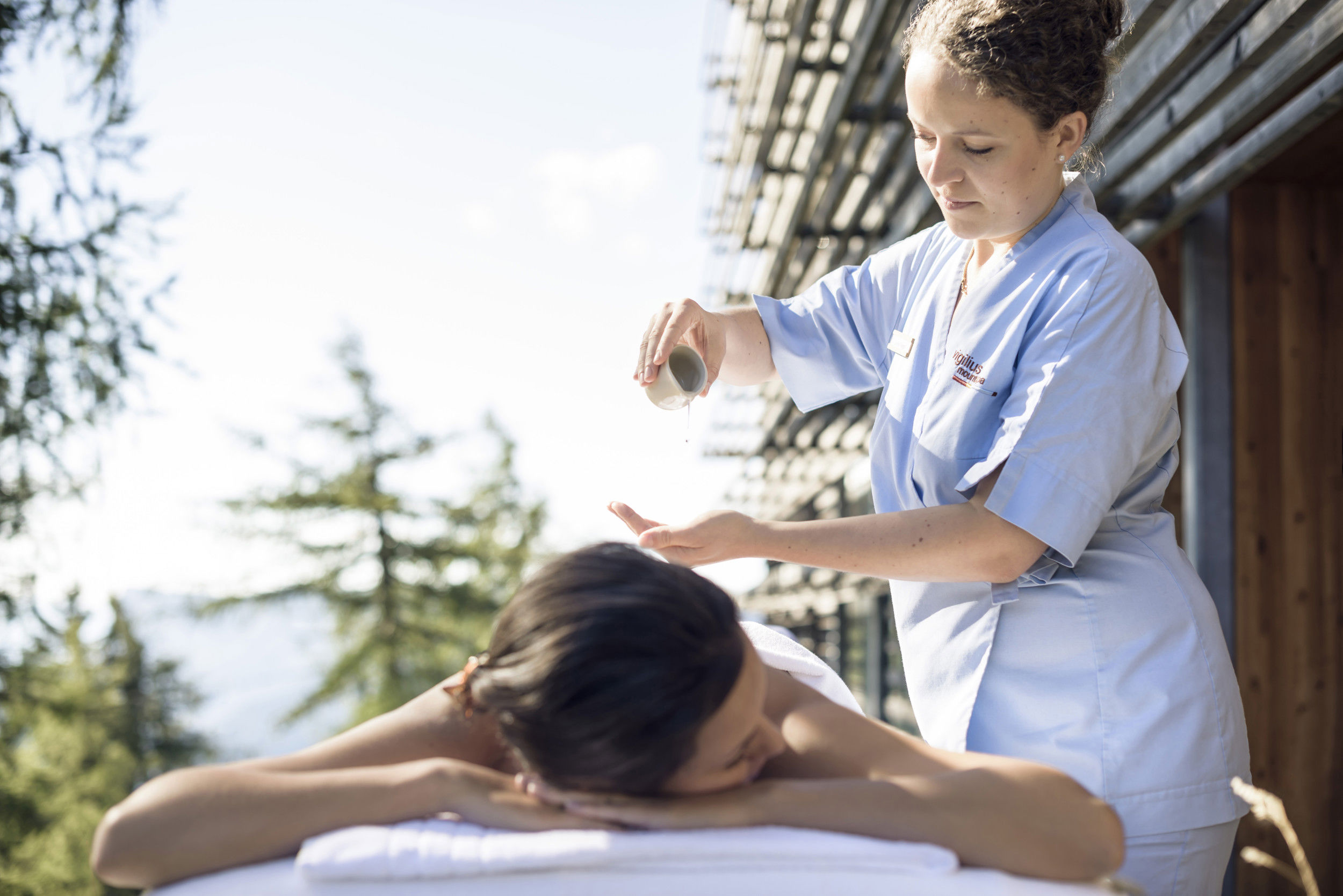 Una donna  sdraiata su un lettino viene massaggiata con dell'olio.