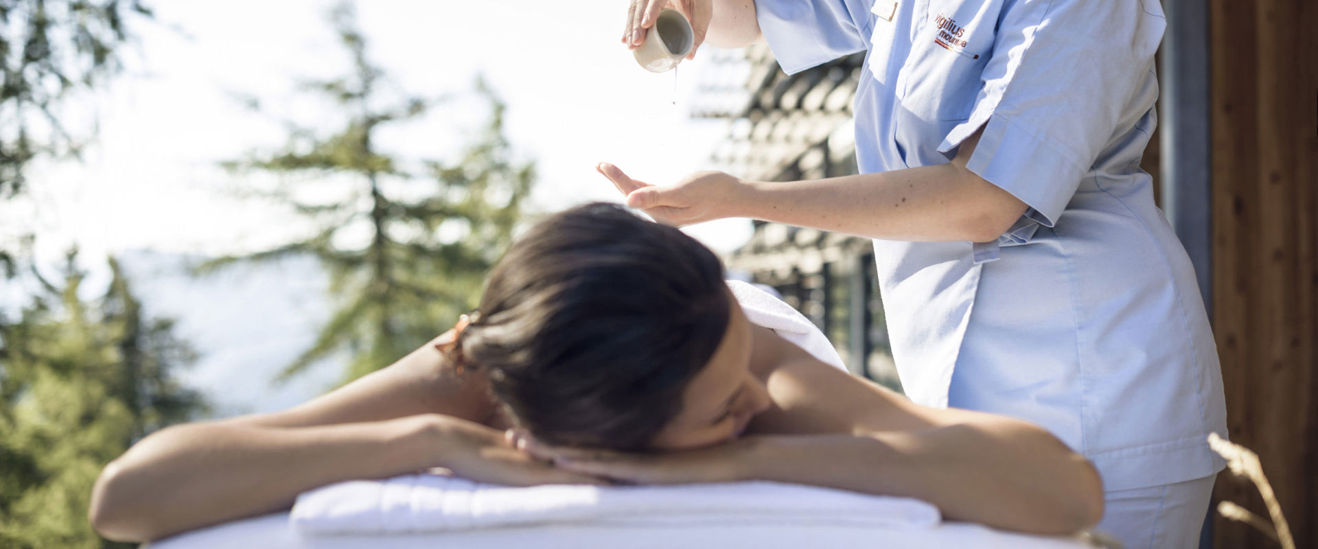 Trattamento benessere Una donna  sdraiata su un lettino viene massaggiata con dell'olio.