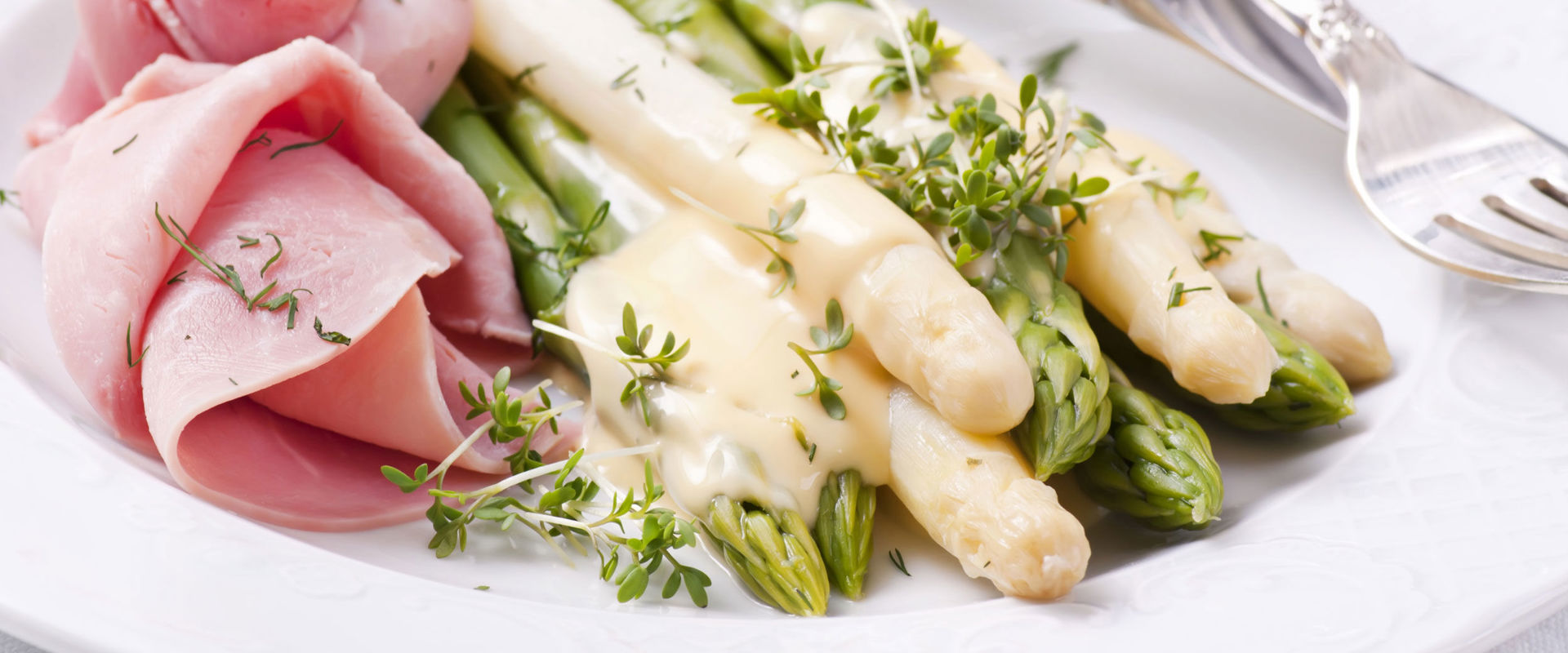 Asparagi con salsa bolzanina Piatto di asparagi bianchi e verdi con prosciutto cotto e salsa bolzanina.