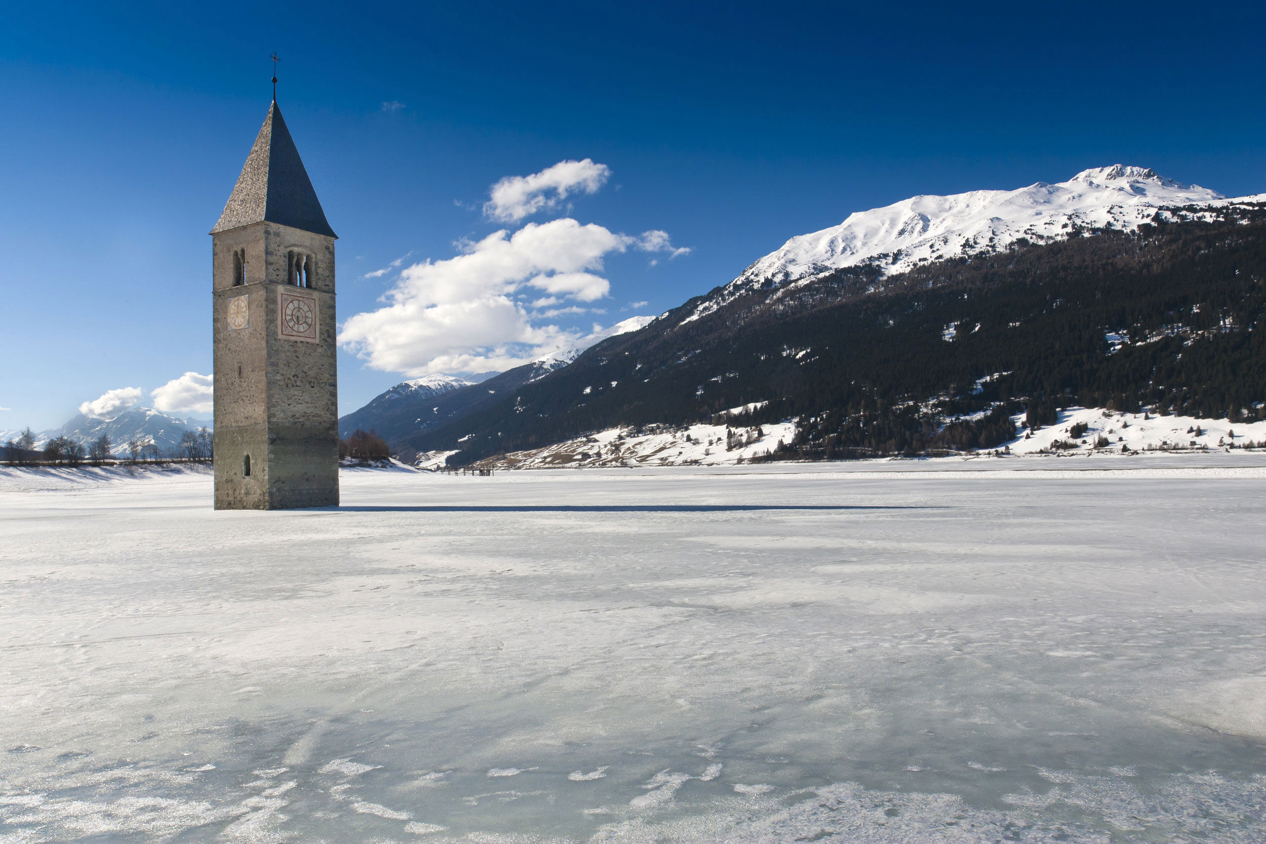 Il campanile della chiesa sommersa emerge dal lago di Resia ghiacciato .