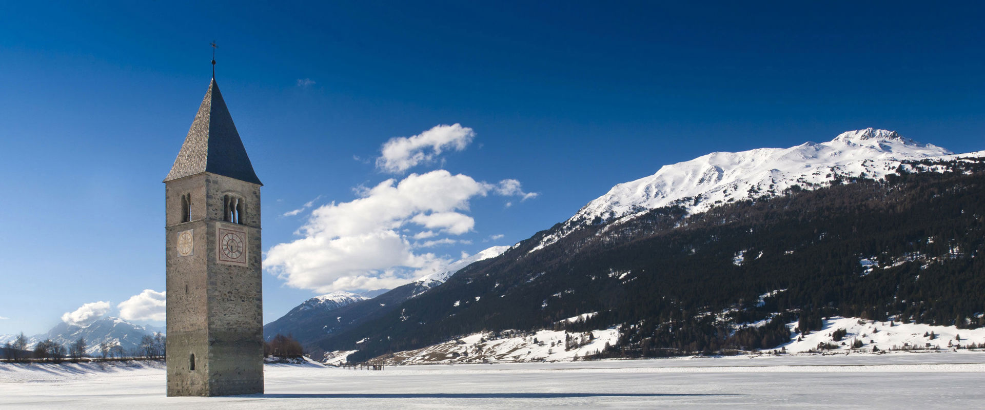 Inverno al Lago di Resia Il campanile della chiesa sommersa emerge dal lago di Resia ghiacciato .