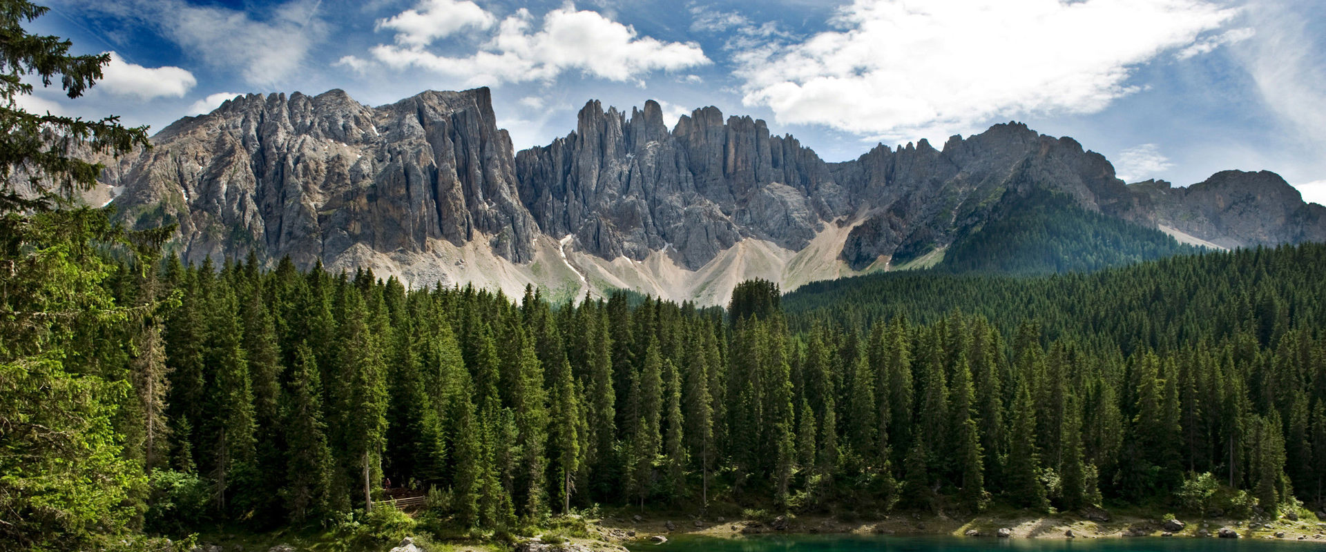 Lago di Carezza in Val d'Ega. Lago turchese di fronte alla foresta e alla catena montuosa.