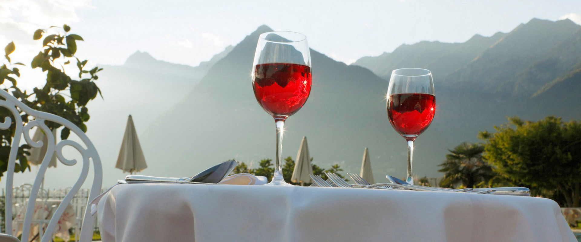 Pranzo all'aperto. Tavola apparecchiata con 2 bicchieri di vino rosso.