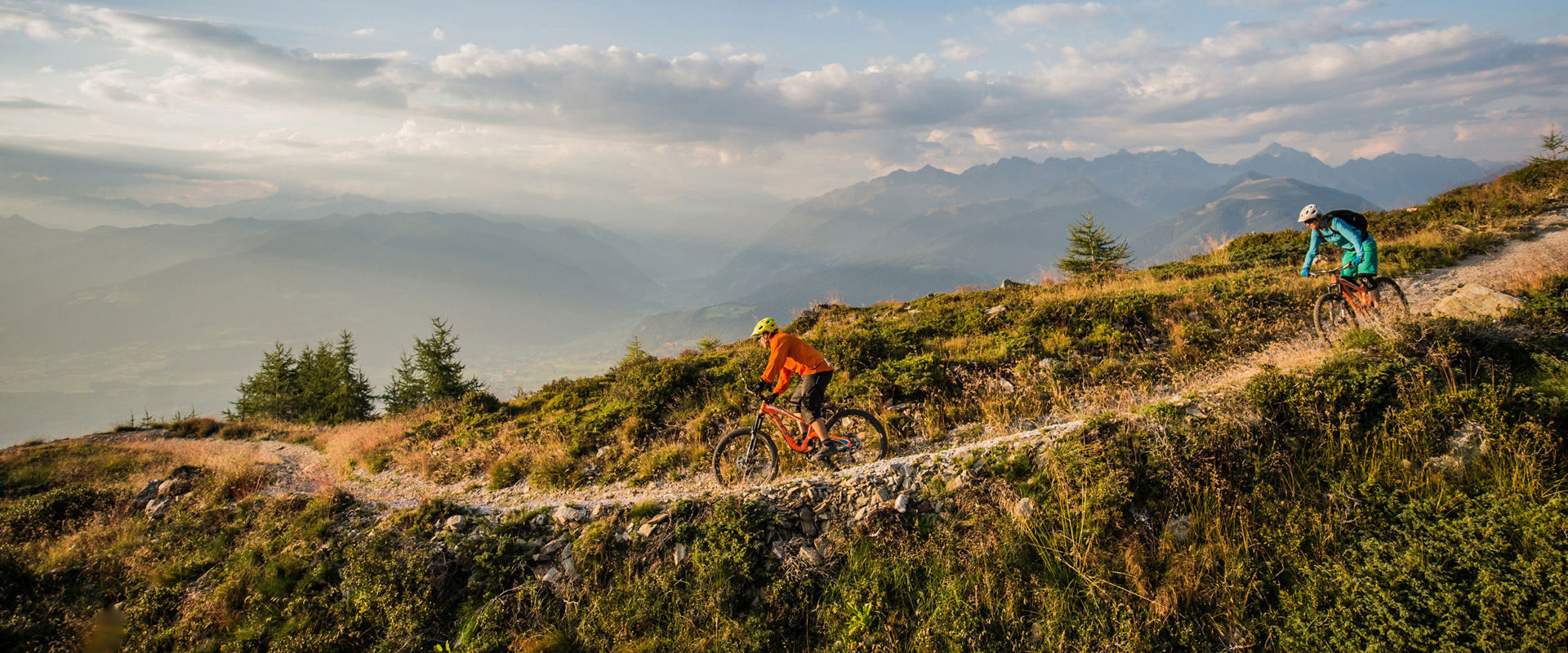 Discesa in bicicletta Due ciclisti percorrono uno stretto sentiero lungo la montagna.