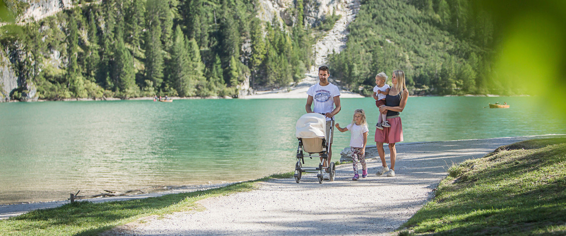 Famiglia di 5 persone passeggia sulle rive del lago con una carrozzina.