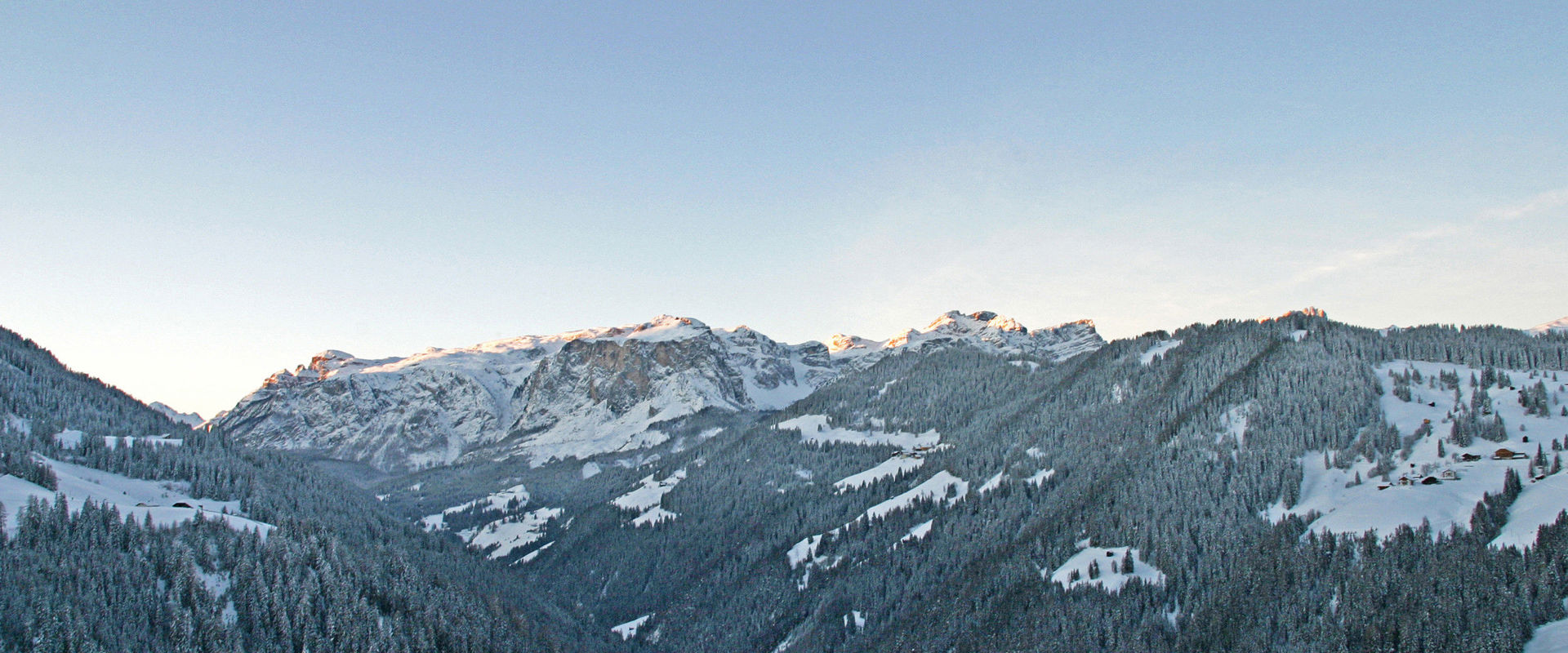 Inverno in Alta Badia. Cime di montagna e pendii innevati e boscosi alle prime luci del mattino.