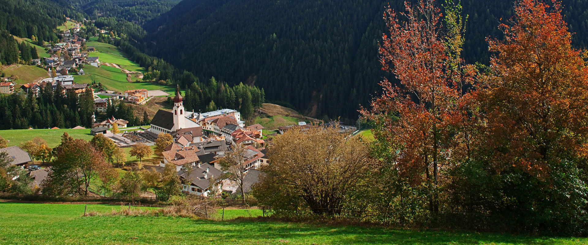 Nova Levante Case e chiesa a Nova Levante in autunno con il Latemar sullo sfondo