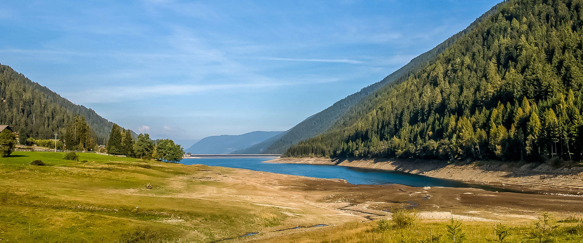 Lago di Zoccolo Serbatoio circondato da prati e boschi verdi.