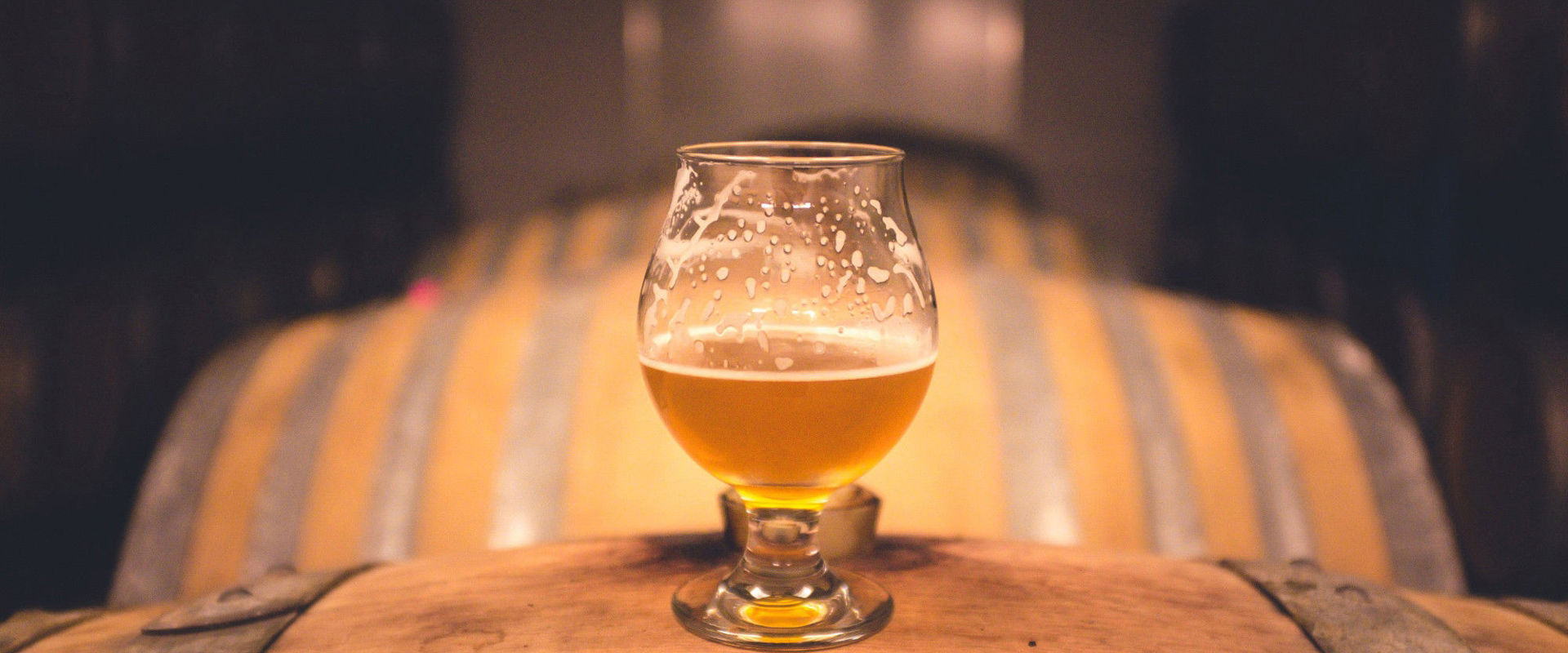 Fusti di birra con mezzo bicchiere di birra in cima.