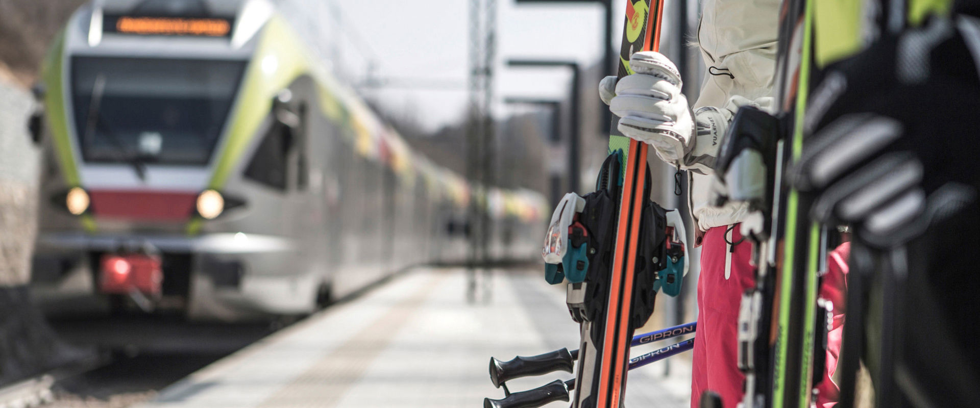 Viaggiare in treno in inverno Gli sciatori aspettano sulla piattaforma mentre il treno arriva alla stazione.