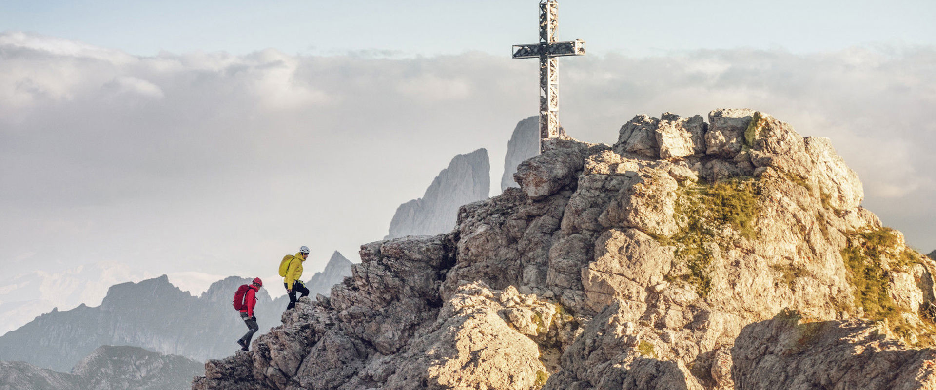 Due escursionisti raggiungono la croce in vetta a una montagna in Val Gardena.
