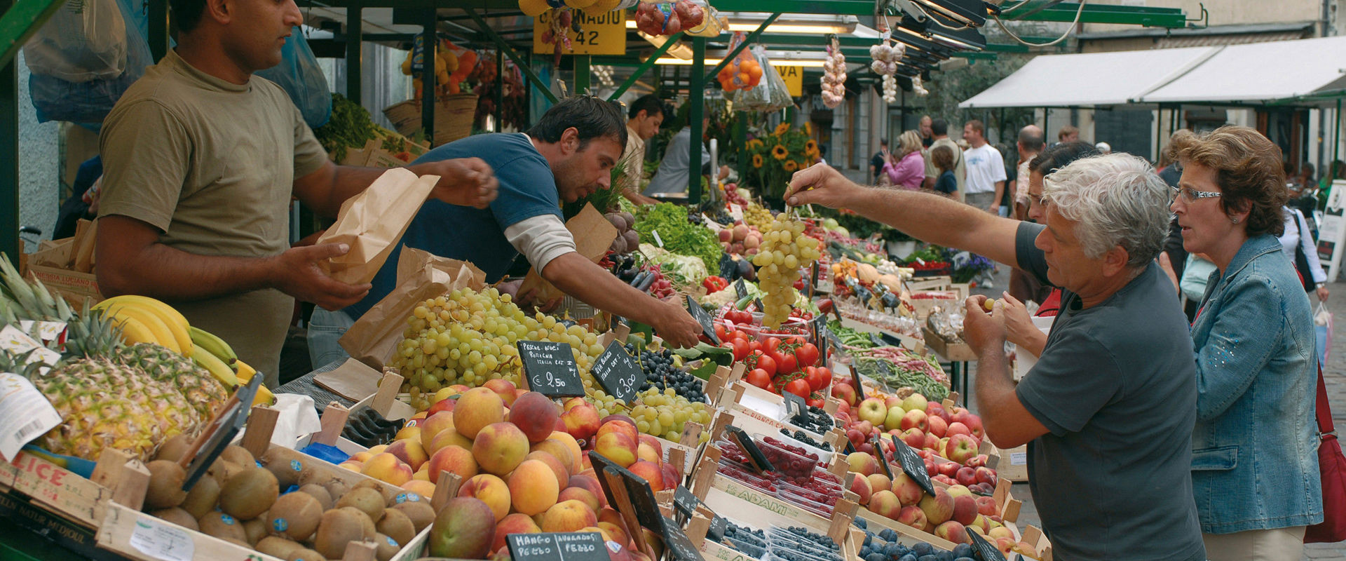 Alcune persone acquistano frutta fresca al mercato del centro città.