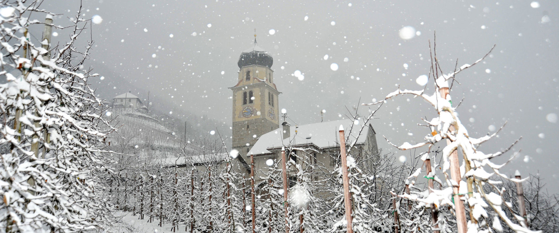 Fiocchi di neve cadono sulla chiesa di pellegrinaggio "Santuario della Madonna dei Sette dolori" a Rifiano.