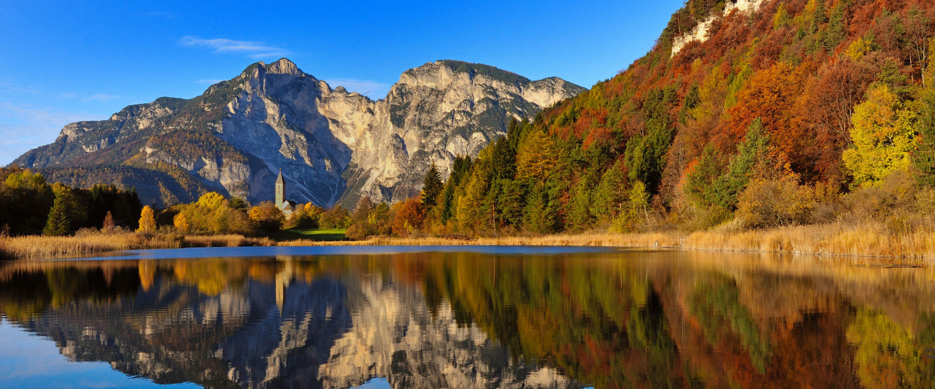 Lago di Favogna in autunno Paesaggio montano autunnale riflesso nel lago blu scuro.