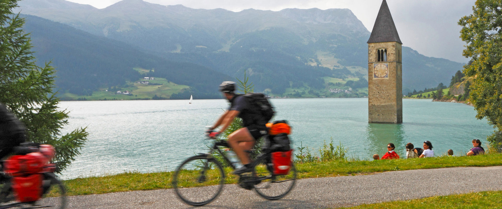 Ciclista passa davanti al lago di Resia.