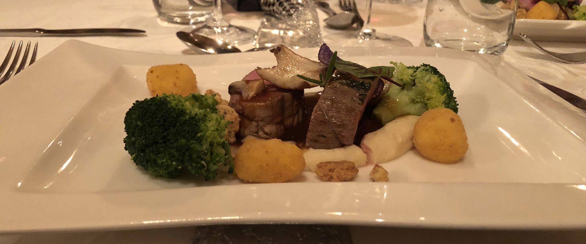 Su un tavolo apparecchiato vine servita carne di cervo in salsa di mirtilli.