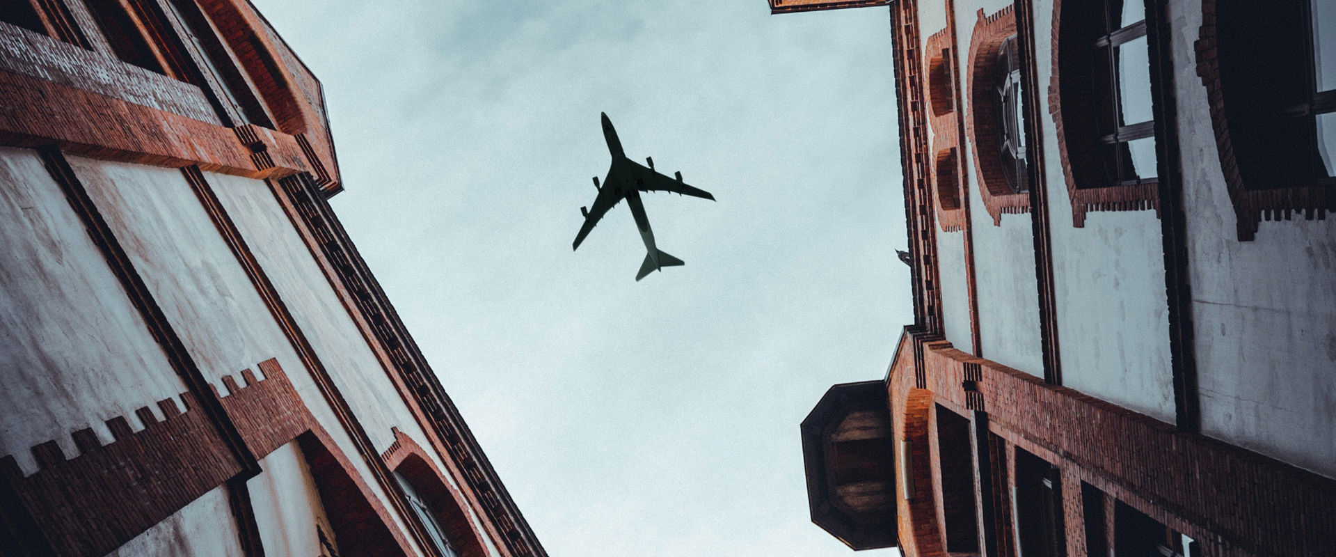 Foto di un aereo dal basso tra le case di un vicolo cittadino.