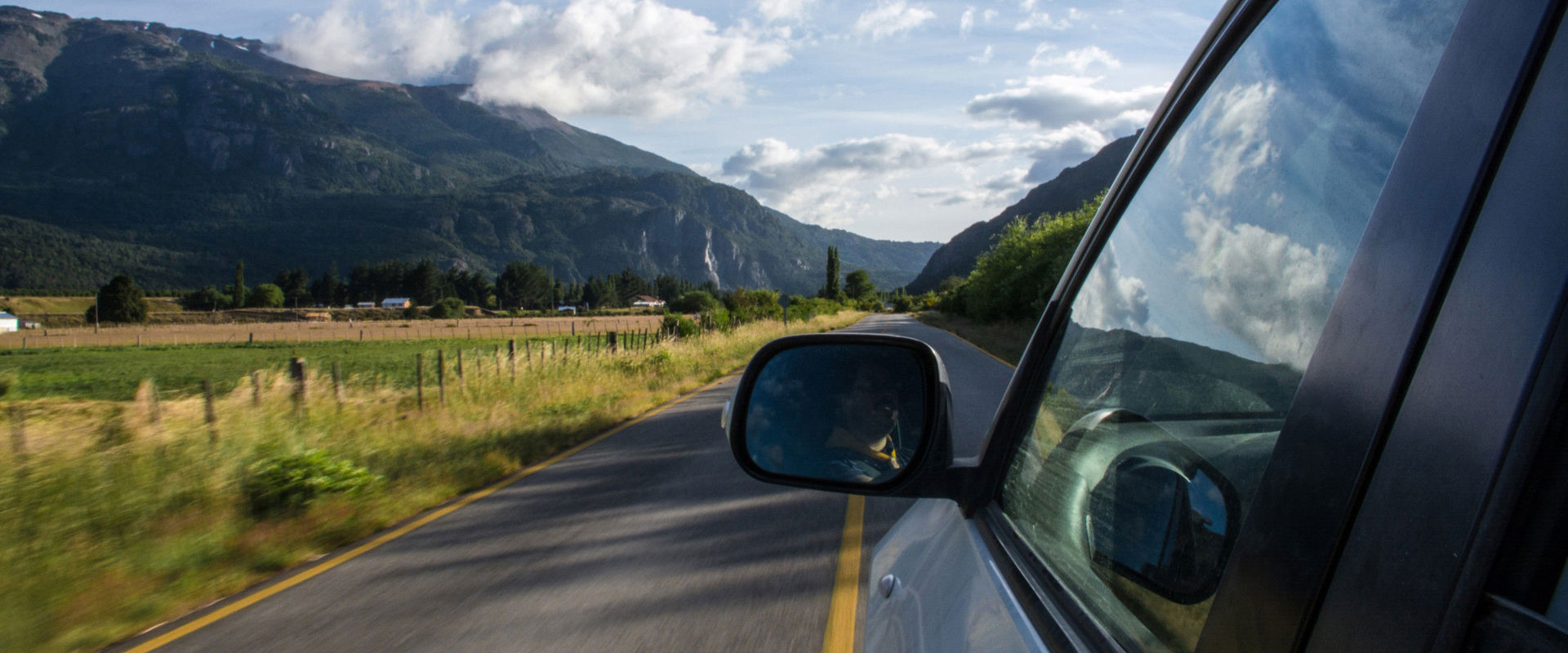 Auto che viaggia su un rettilineo. Foto dal finestrino posteriore sinistro dell'auto con vista sul lato del conducente, sulla strada diritta e sull'area circostante.