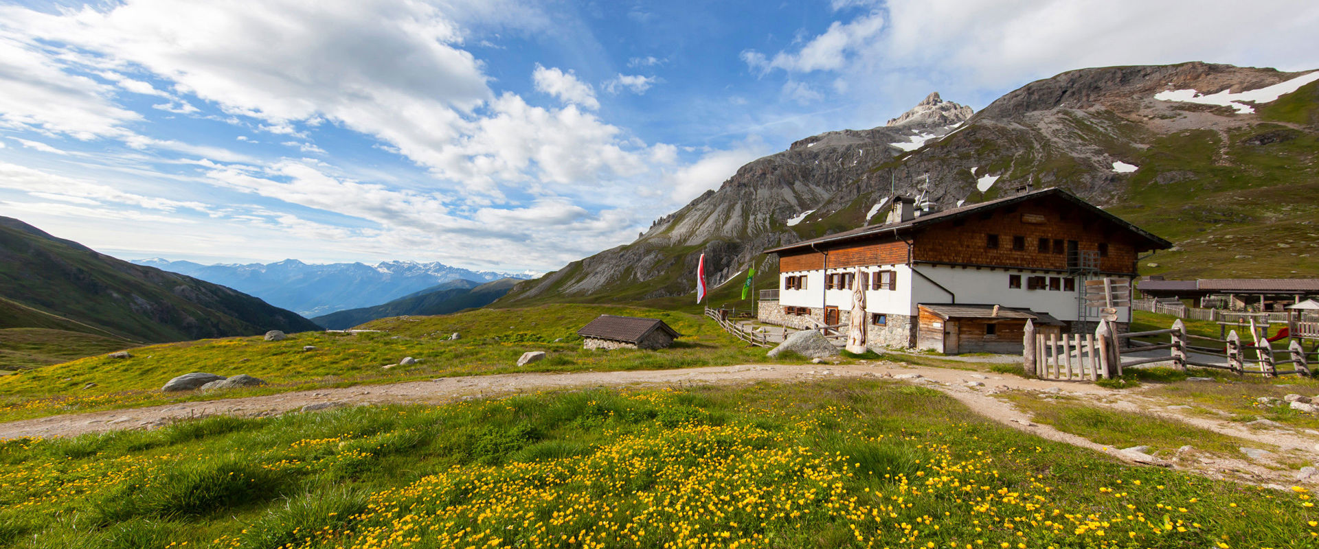 Rifugio Sesvenna - tour d'alta quota Alto Adige Vista sul Rifugio Sesvenna d'estate con fiori gialli che lo circondano
