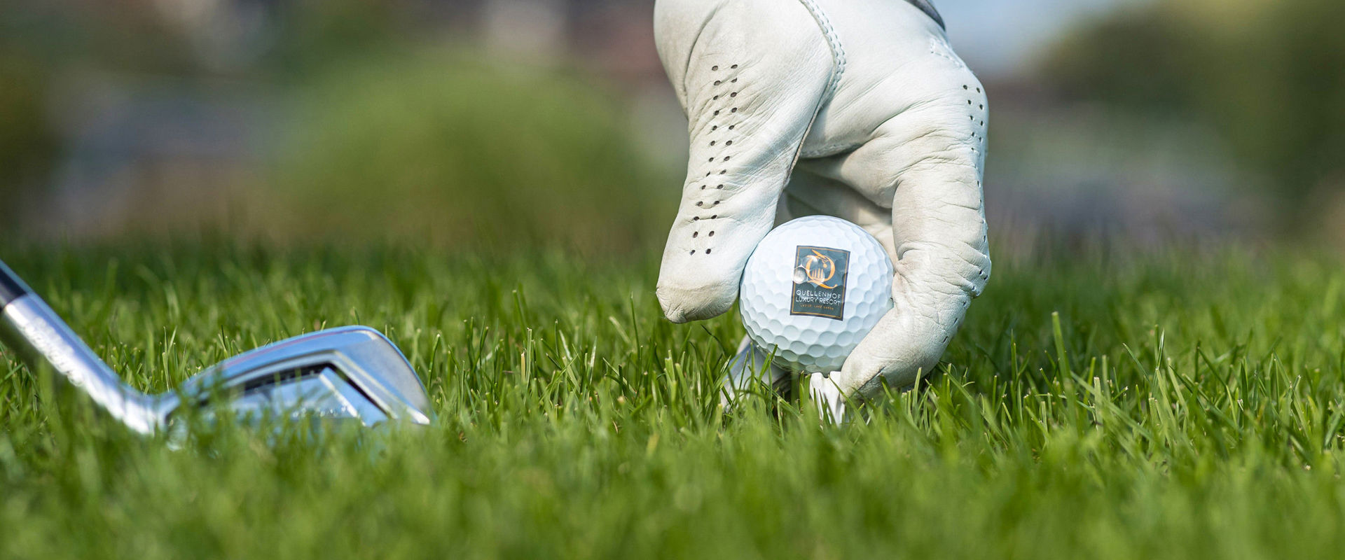 Campo da golf Quellenhof La mano posiziona la pallina da golf sull'erba per il tee shot.