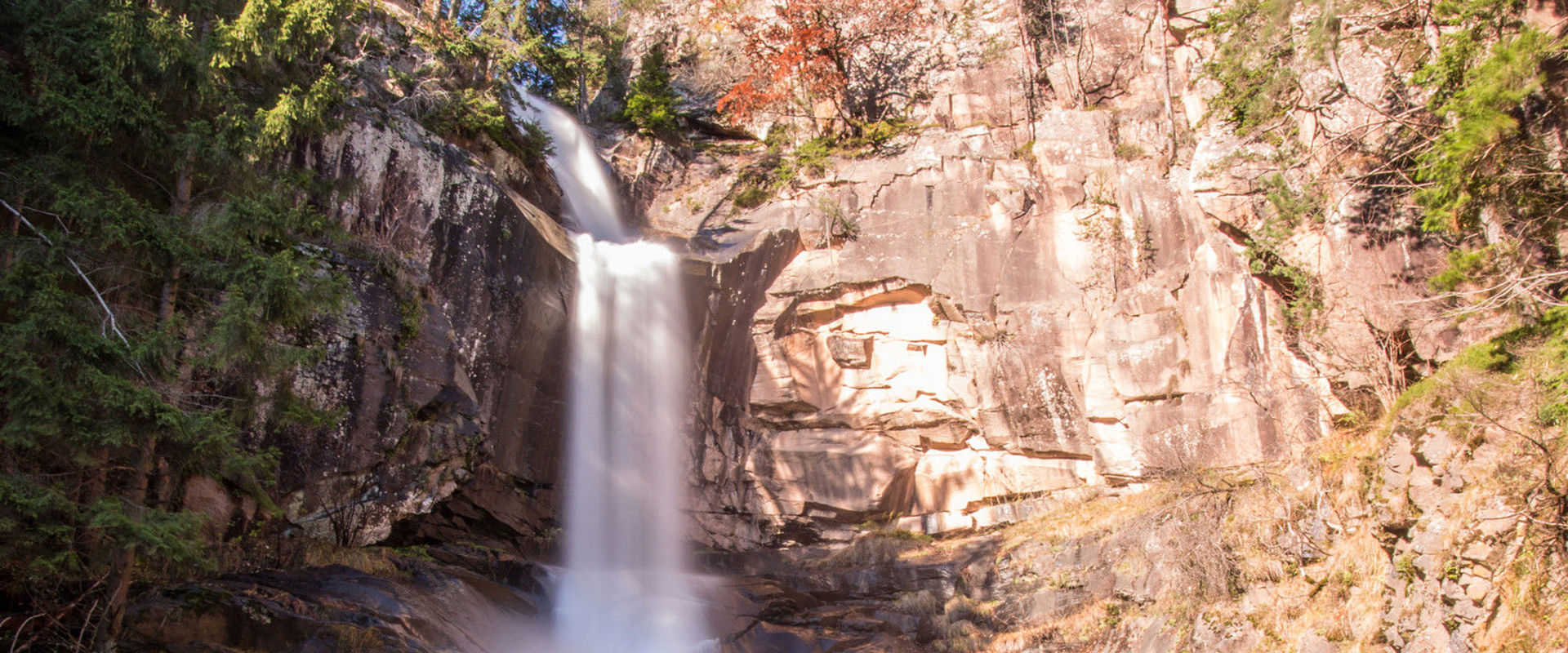 Cascata di Barbiano La cascata scende scrosciante dalla ripida parete rocciosa.