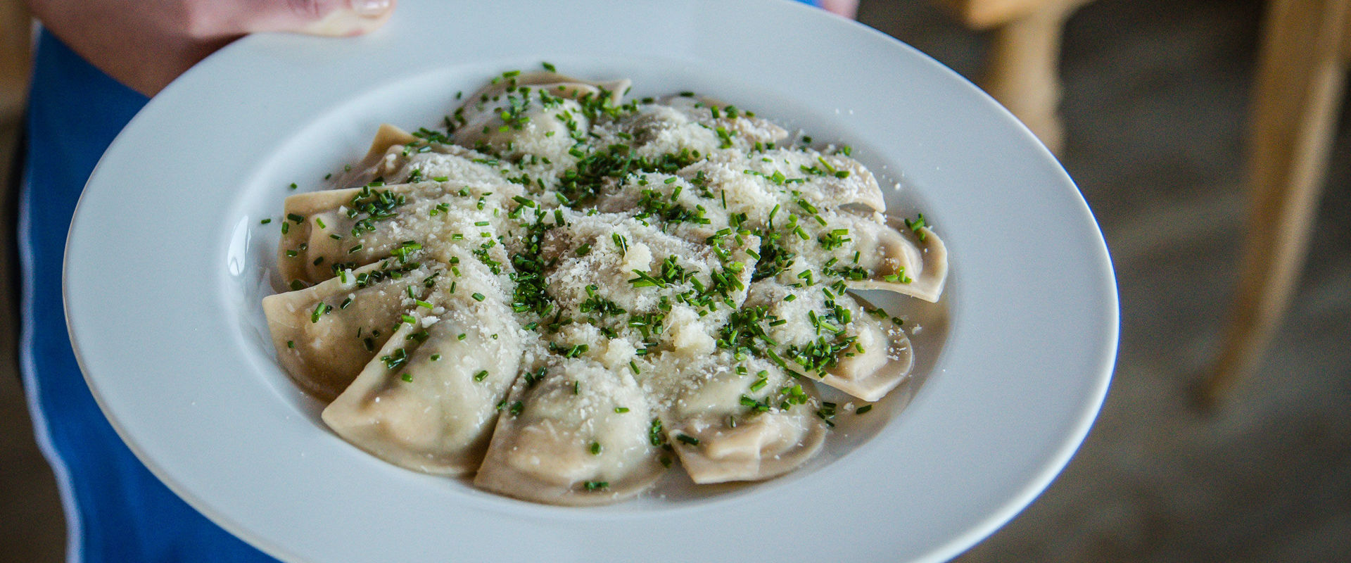 La cameriera porta un piatto con Schlutzkrapfen.