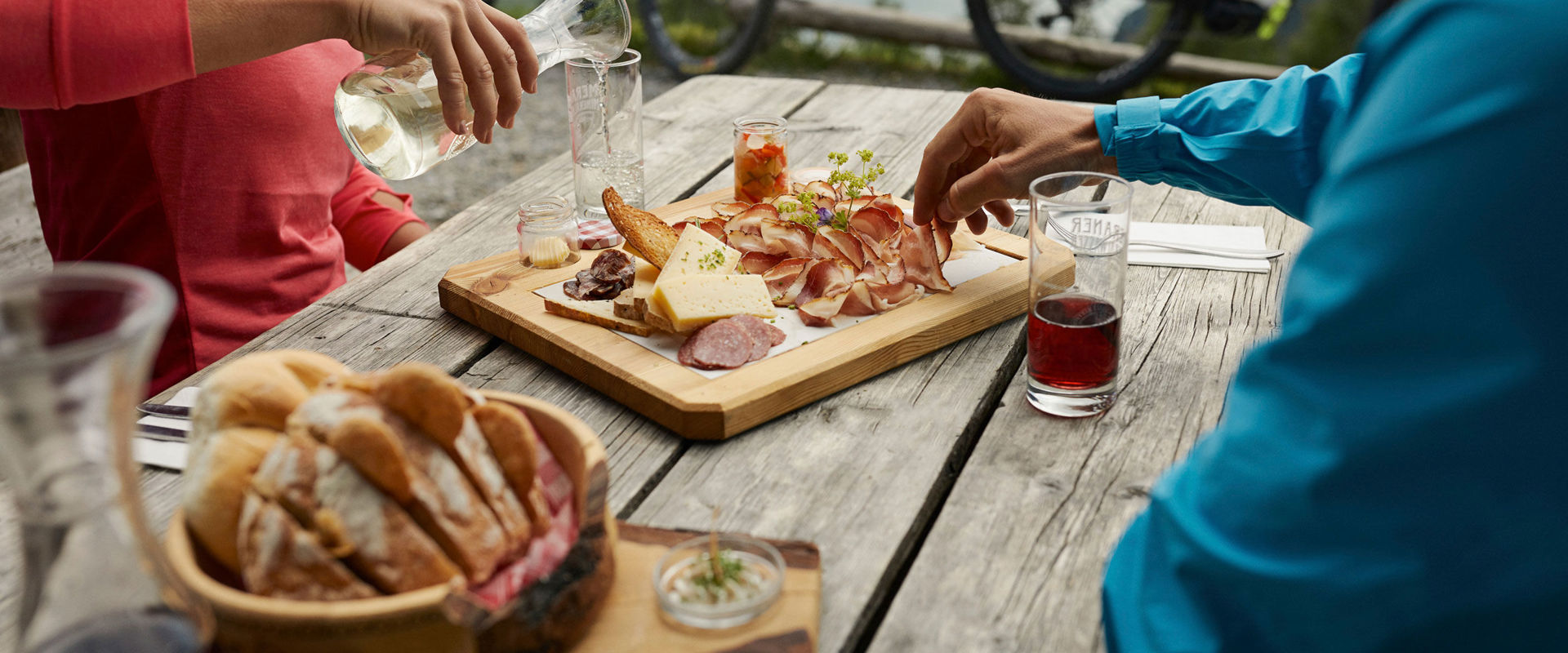 Ciclisti siedono su un tavolo di legno e mangiano uno spuntino.