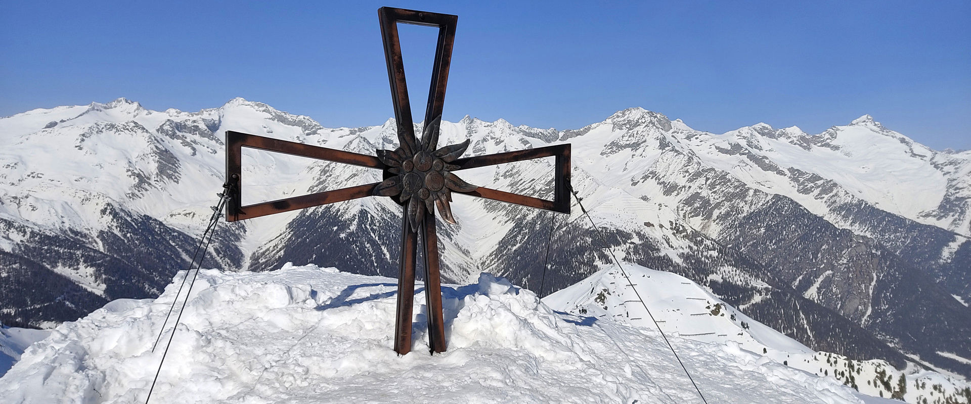 Croce di vetta dello Speikboden Croce di vetta dello Speikboden con vista panoramica sulle vette circostanti innevate.