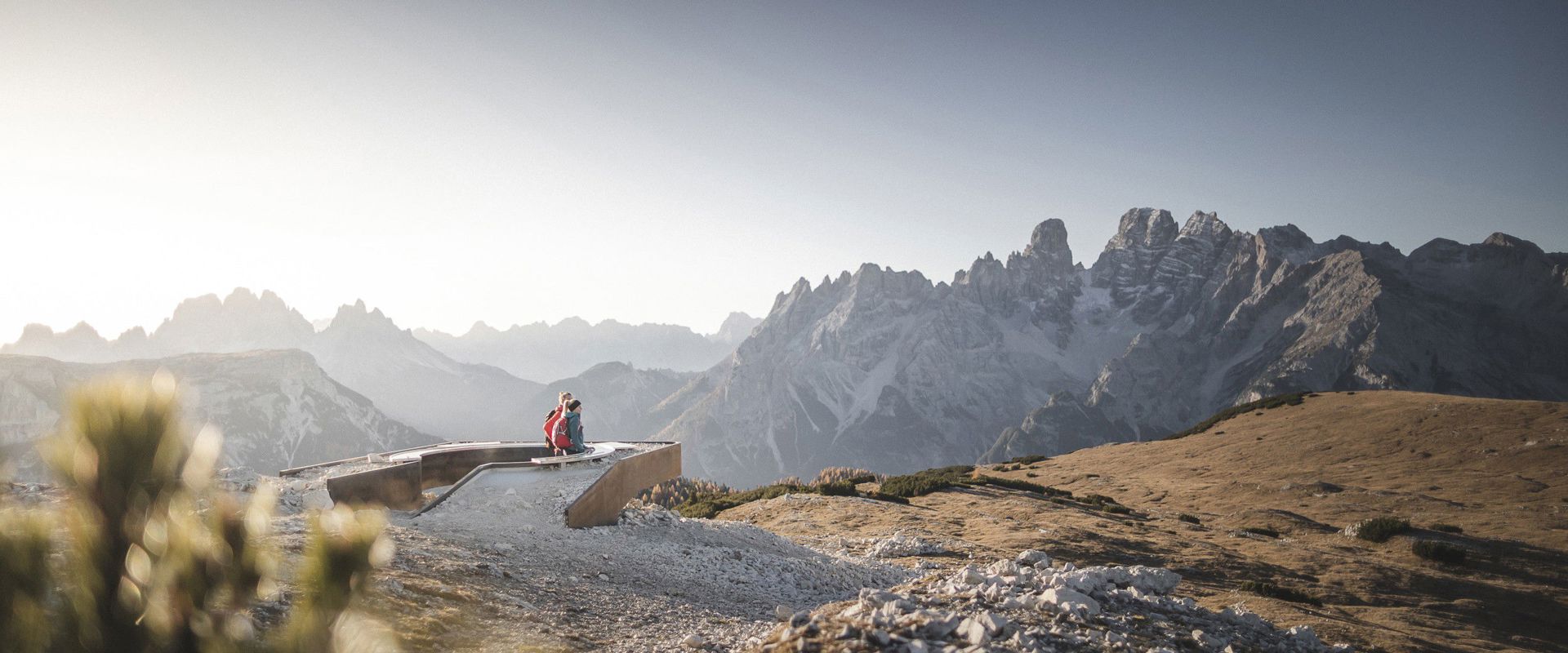 Una coppia siede in un punto panoramico e guarda le rocce nude delle Dolomiti.