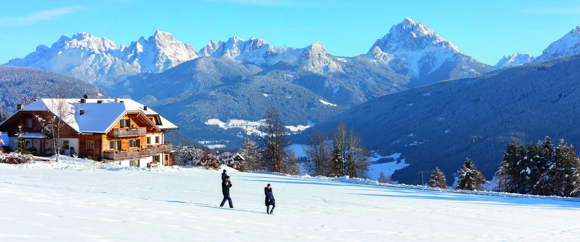 Una famiglia di tre persone passeggia sul prato innevato.