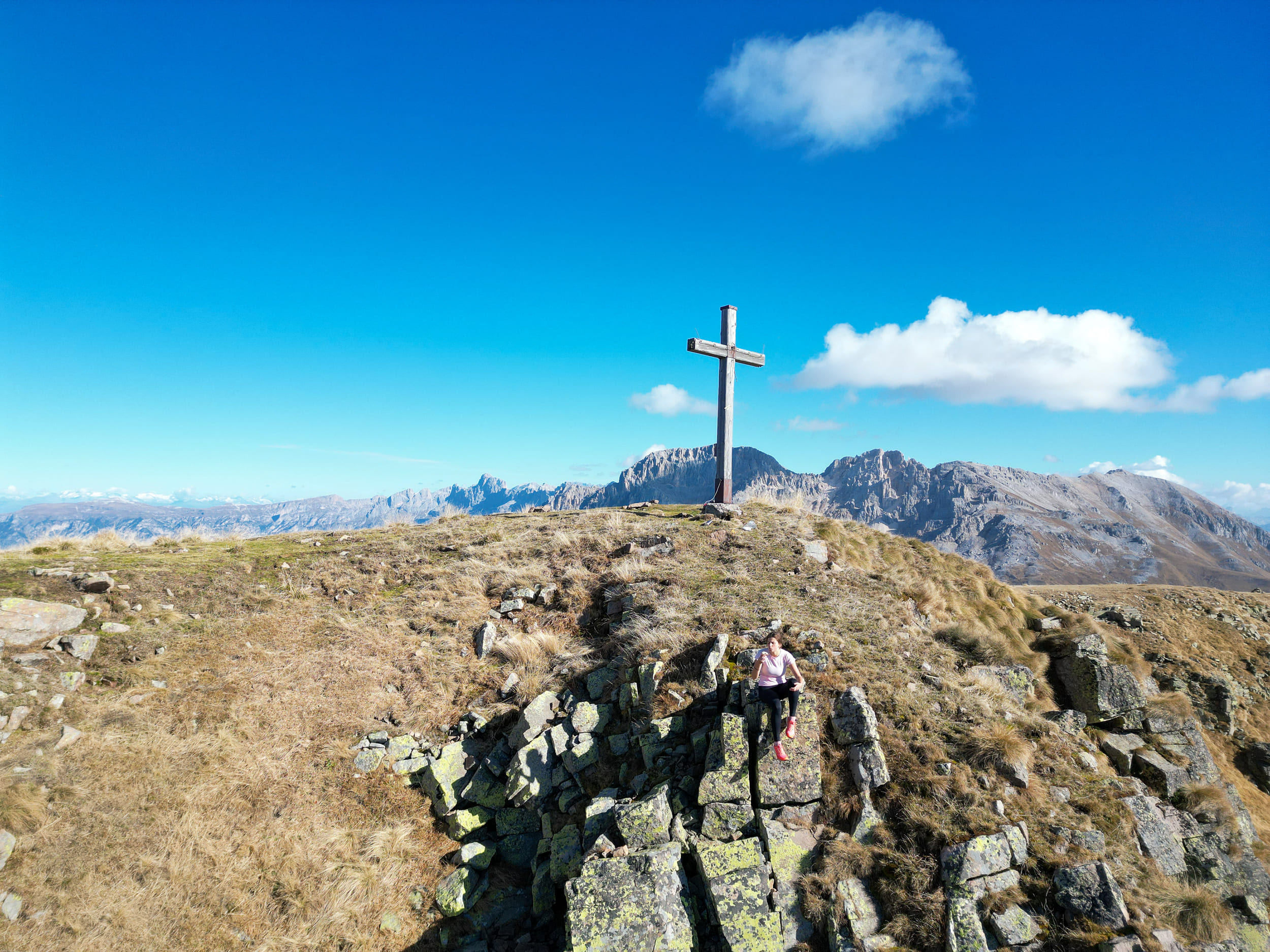 Escursionista sulla cima di una montagna con croce