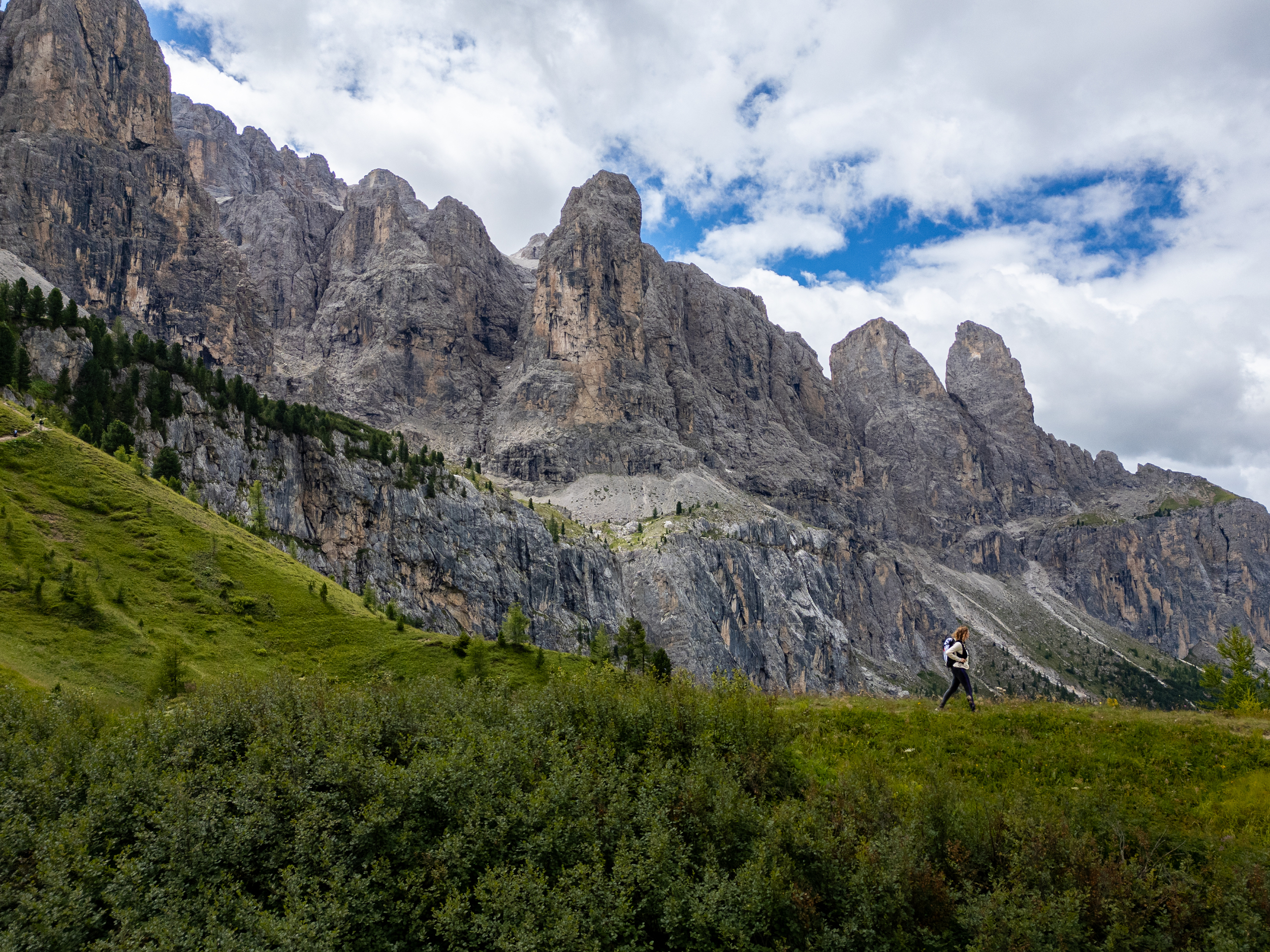 Escursionista su un prato di montagna con pareti rocciose sullo sfondo