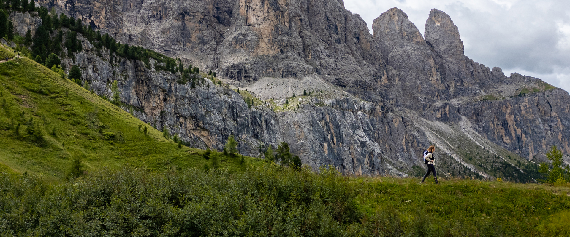 Passo Gardena Escursionista su un prato di montagna con pareti rocciose sullo sfondo