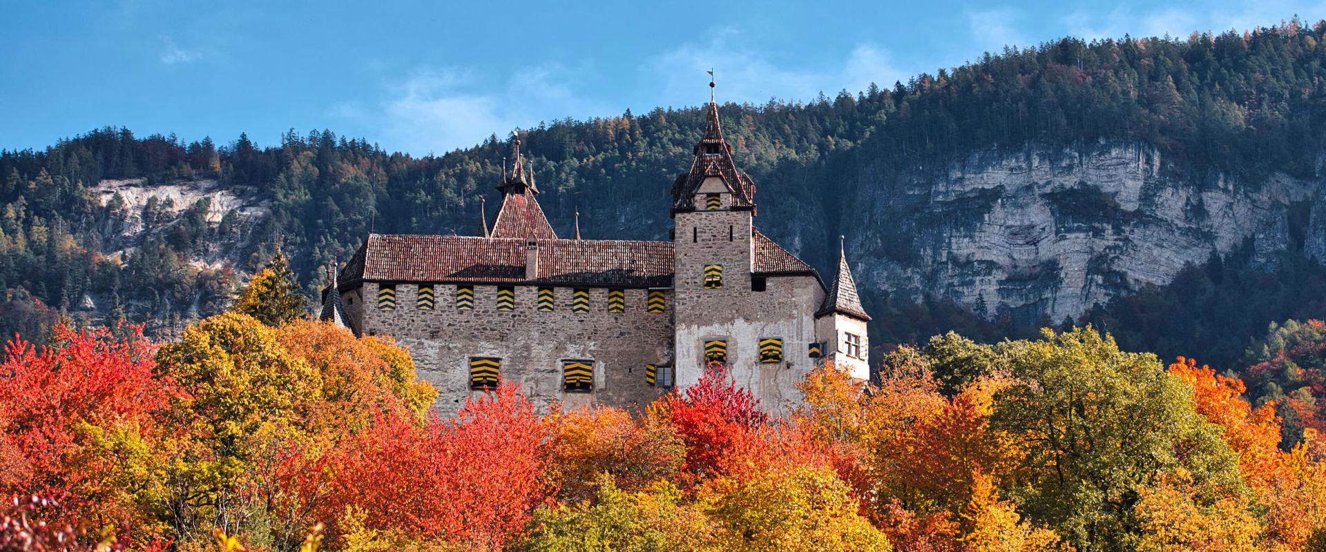 Castel d'Enna in autunno Vista del castello di Enn immerso in un paesaggio autunnale di alberi colorati.