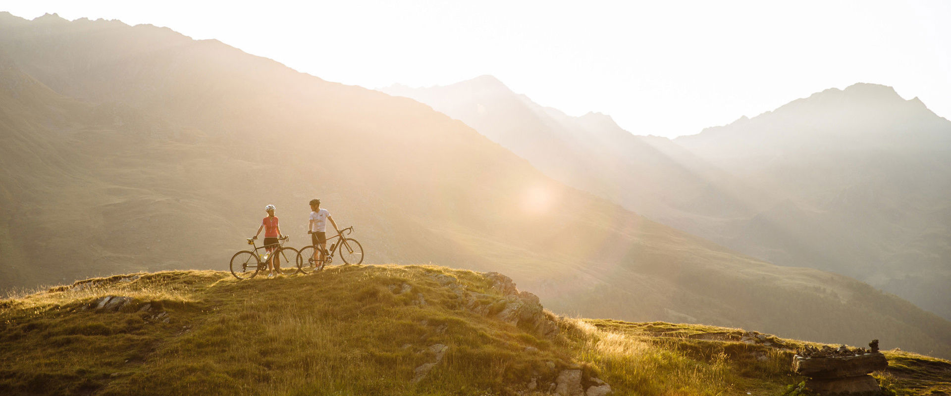 In bicicletta in montagna 2 ciclisti si trovano nel mezzo di un paesaggio montano mozzafiato.