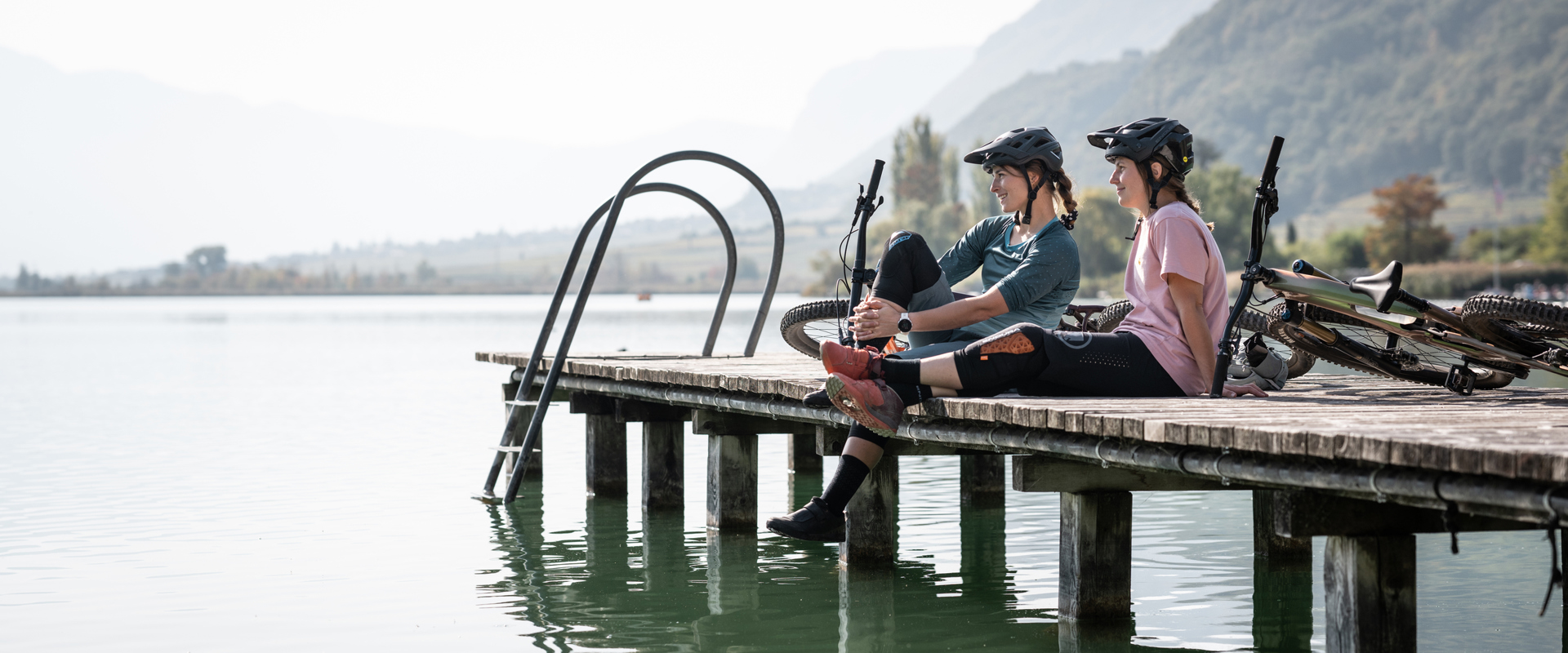 2 ciclisti sul molo di un lago in Alto Adige
