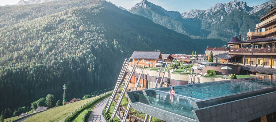 Terrazza dell'hotel con sky pool e vista mozzafiato sulle montagne.