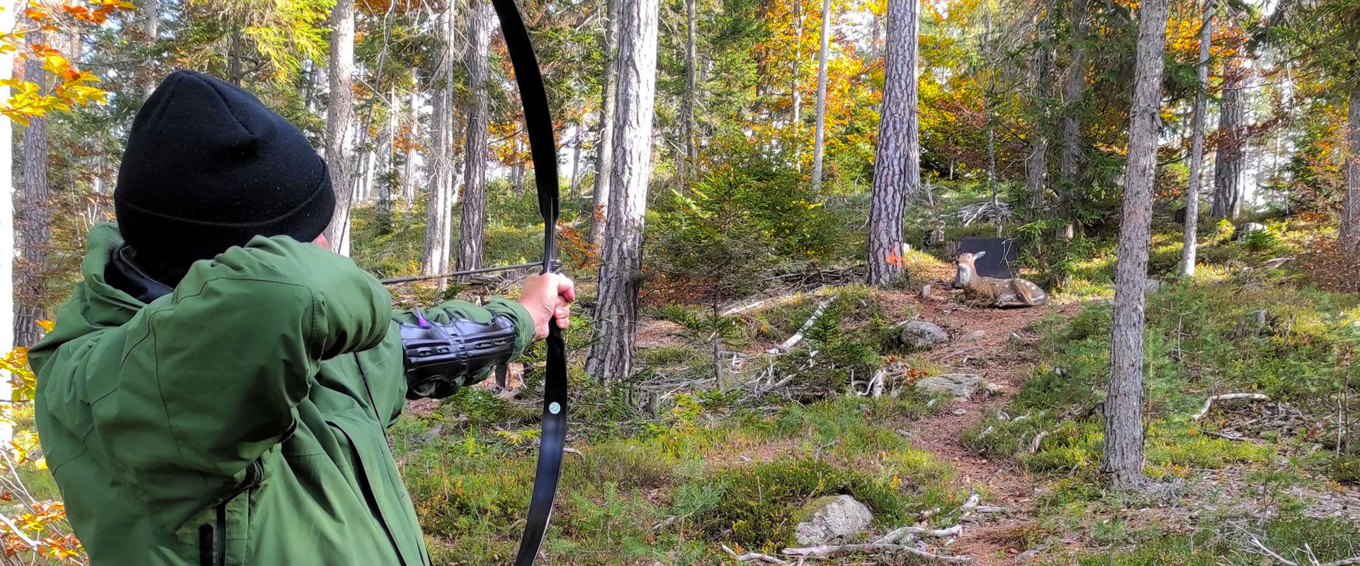 Percorso di tiro con l'arco 3D RiArco, nel bosco nei pressi di Auna di Sopra Un uomo prendere la mira per colpire un bersaglio in legno nel parco di tiro con l'arco a Renon.