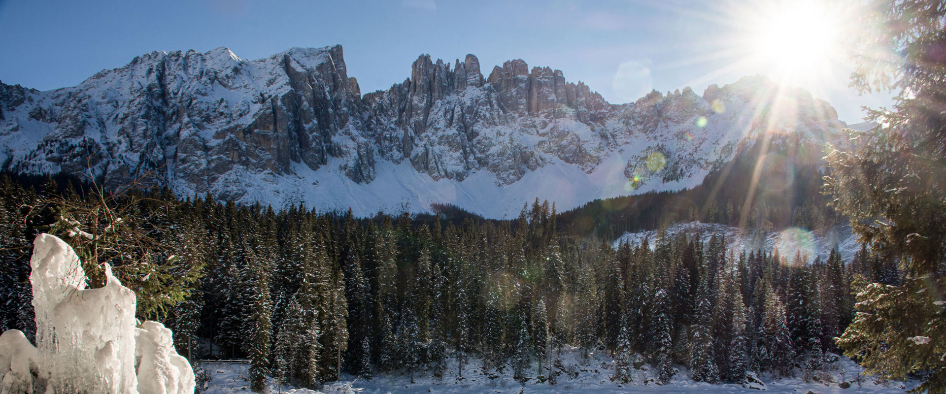 Lago di Carezza in inverno Donna ammira il lago innevato sulla riva.