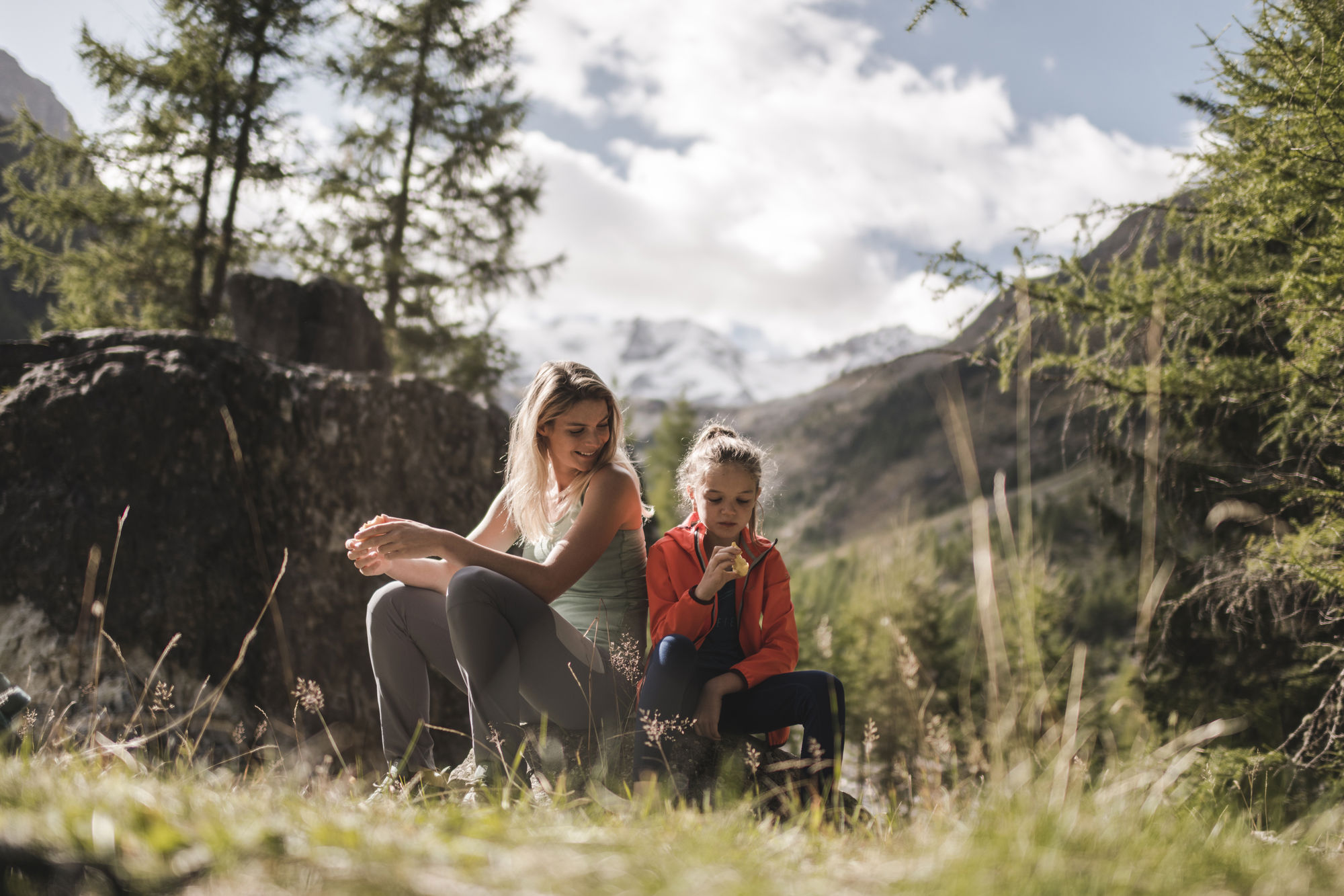 Madre e figlia sedute su una pietra in montagna.