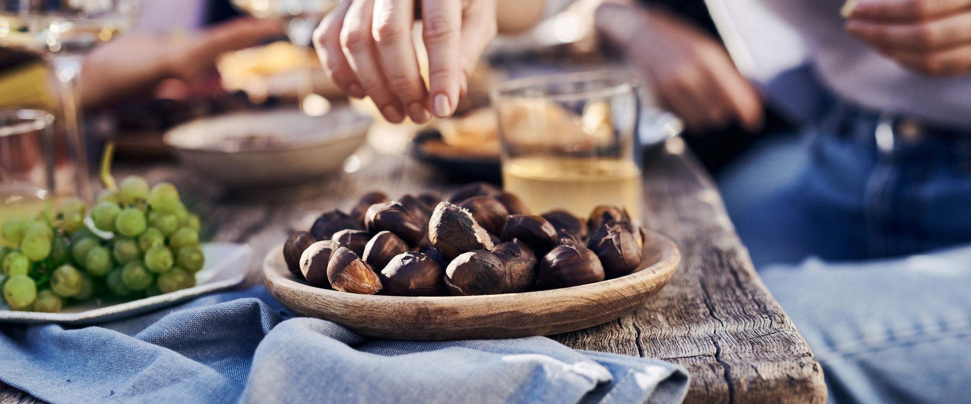 Tavolo di legno con uva, castagne e vino.