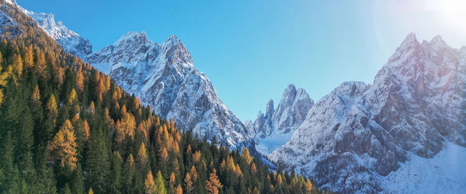 Vista sulla Val Fiscalina con alberi autunnali e montagne innevate