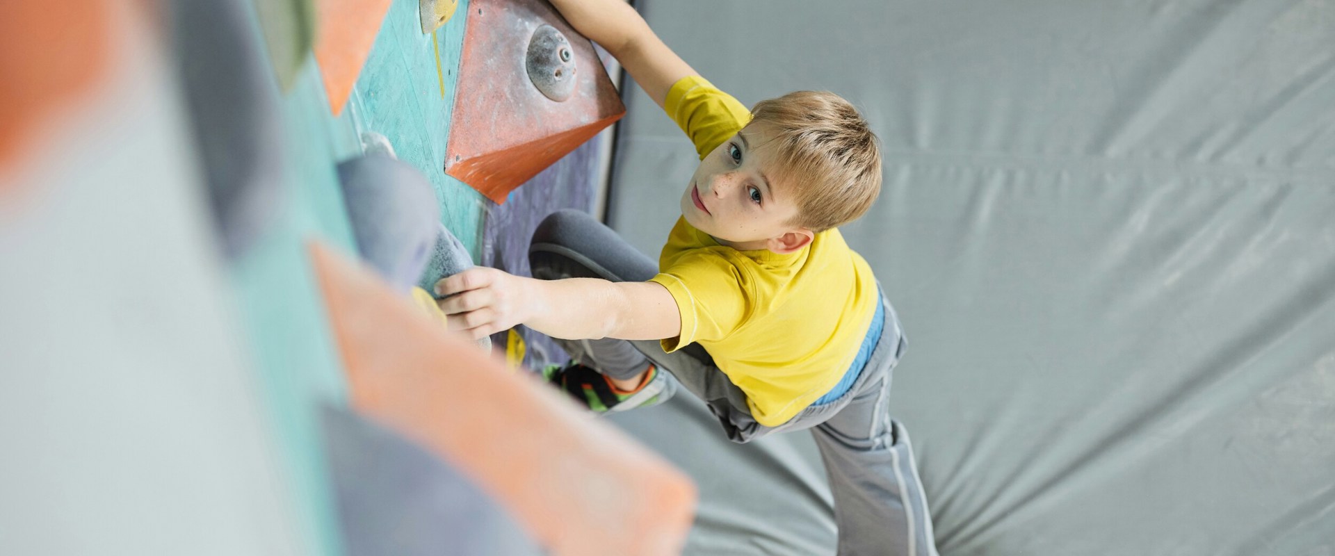 Bambino su parete da arrampicata in palestra