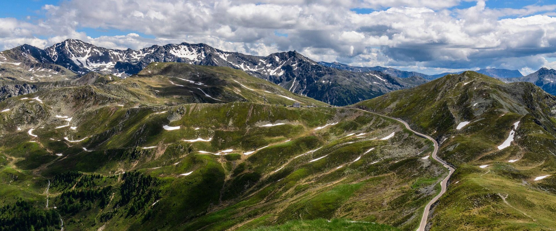 Vista sul Passo di Pennes, sulla strada del passo e sul paesaggio montano dal sentiero escursionistico