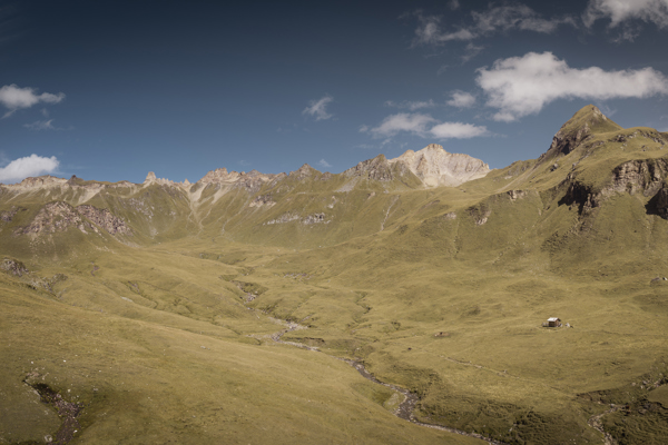 Dolci prati alpini, rifugi e cime montuose all'orizzonte