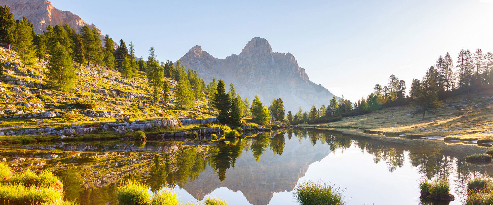 Parco Naturale Fanes-Senes-Braies Lago in mezzo a prati verdi, alberi e un paesaggio montano mozzafiato.