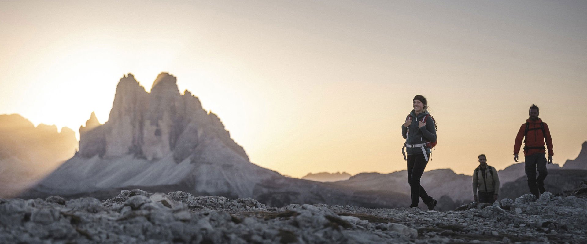 Un gruppo di escursionisti scala le montagne delle Dolomiti al sorgere del sole.
